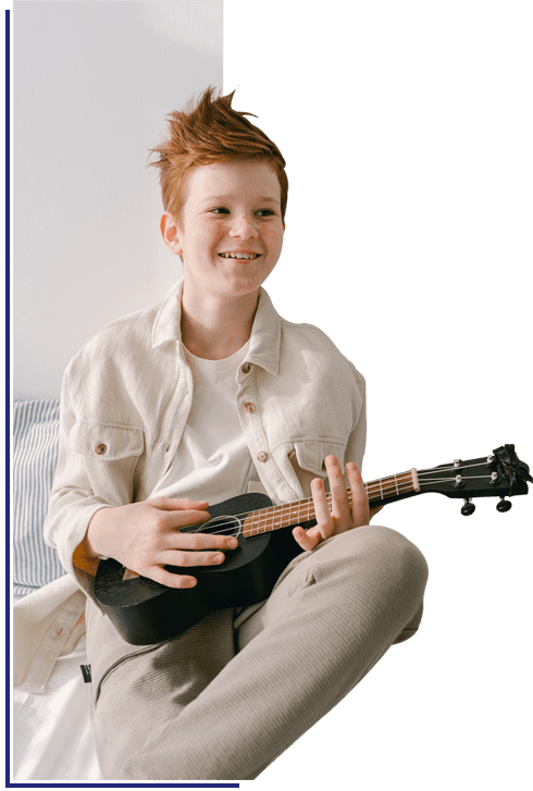 A young boy sitting down playing an instrument.