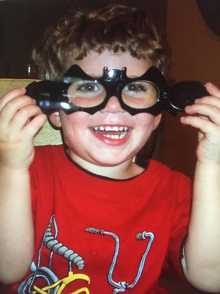 A young boy wearing glasses and smiling.